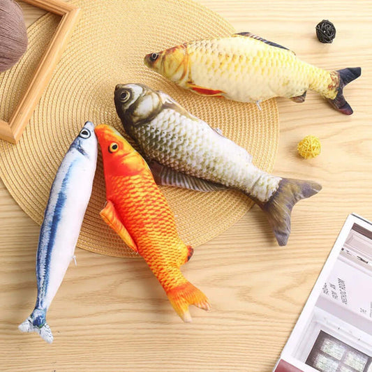 Four fish-shaped toys on a wooden surface with a straw hat and newspaper.