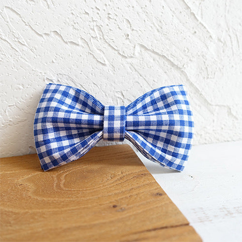 Blue and white checkered bow tie on a wooden surface with a white textured background