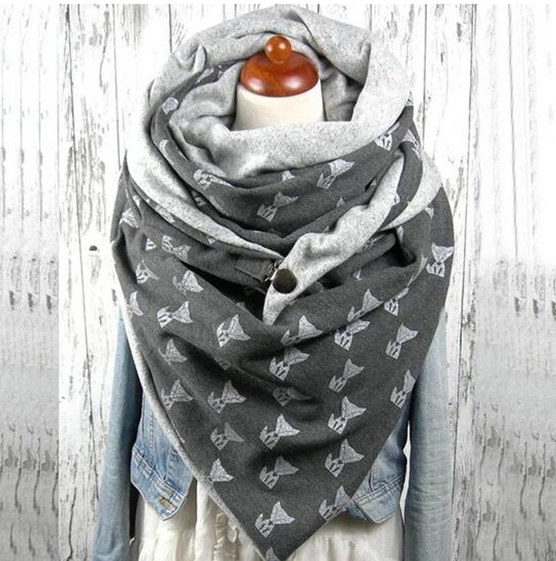 Gray scarf with white patterns draped over a mannequin on a wooden background