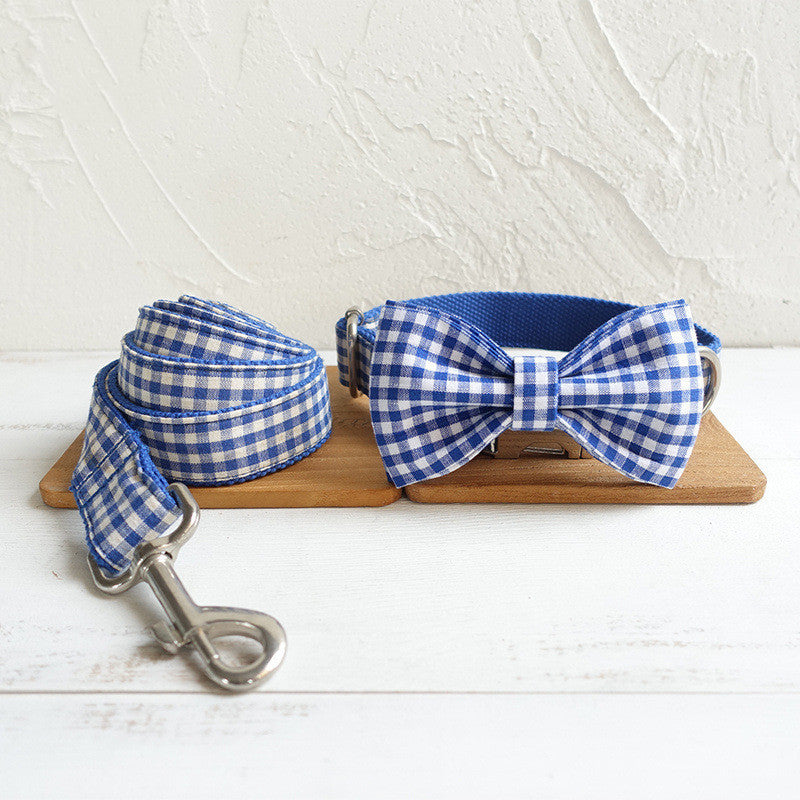 Blue and white checkered dog collar, bow tie, and leash on a wooden board with a light background