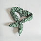 Green and white patterned scarf on a light gray background