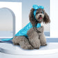 Dog wearing a blue outfit with a hood and headband on a white platform.