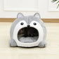 Gray and white pet bed shaped like a fox on a wooden floor.
