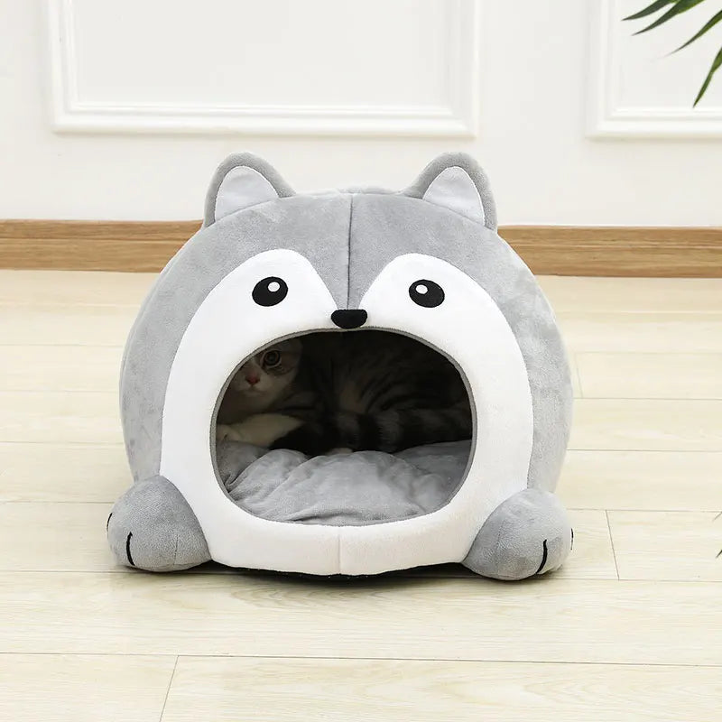 Gray and white pet bed shaped like a fox on a wooden floor.