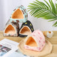 Four small pet houses with different patterns on a wooden surface.