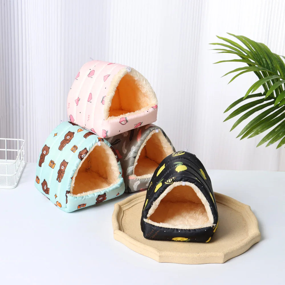 Four pet houses with different patterns on a white surface with a plant in the background
