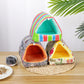 Colorful pet houses on a wooden surface with a small hamster beside them.