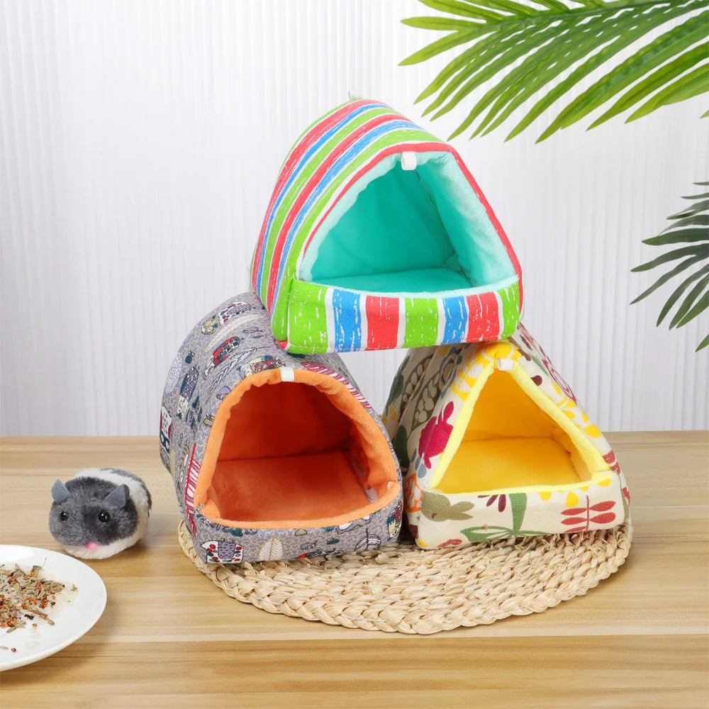 Colorful pet houses on a wooden surface with a small hamster beside them.