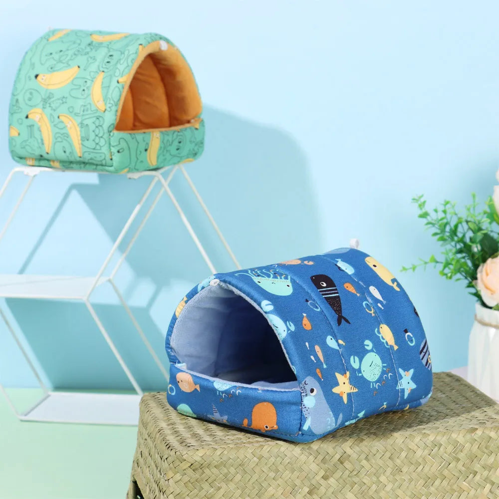 Two pet beds, one green with banana pattern and one blue with sea creature pattern, on a light blue background.