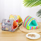 Three colorful pet houses on a wooden surface with a white plate of food.