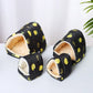 Pair of black slippers with yellow lemon pattern on a white surface.