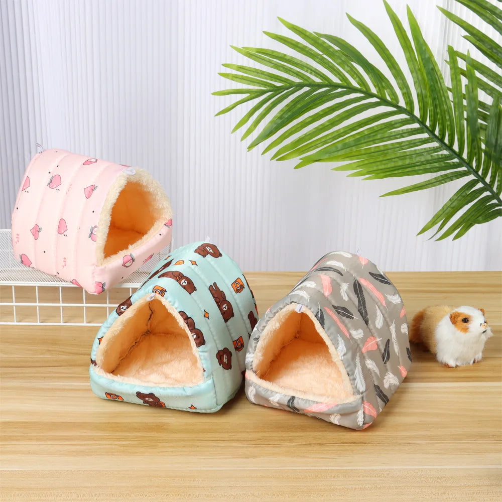 Three small pet houses with different patterns on a wooden surface with a green leaf in the background.