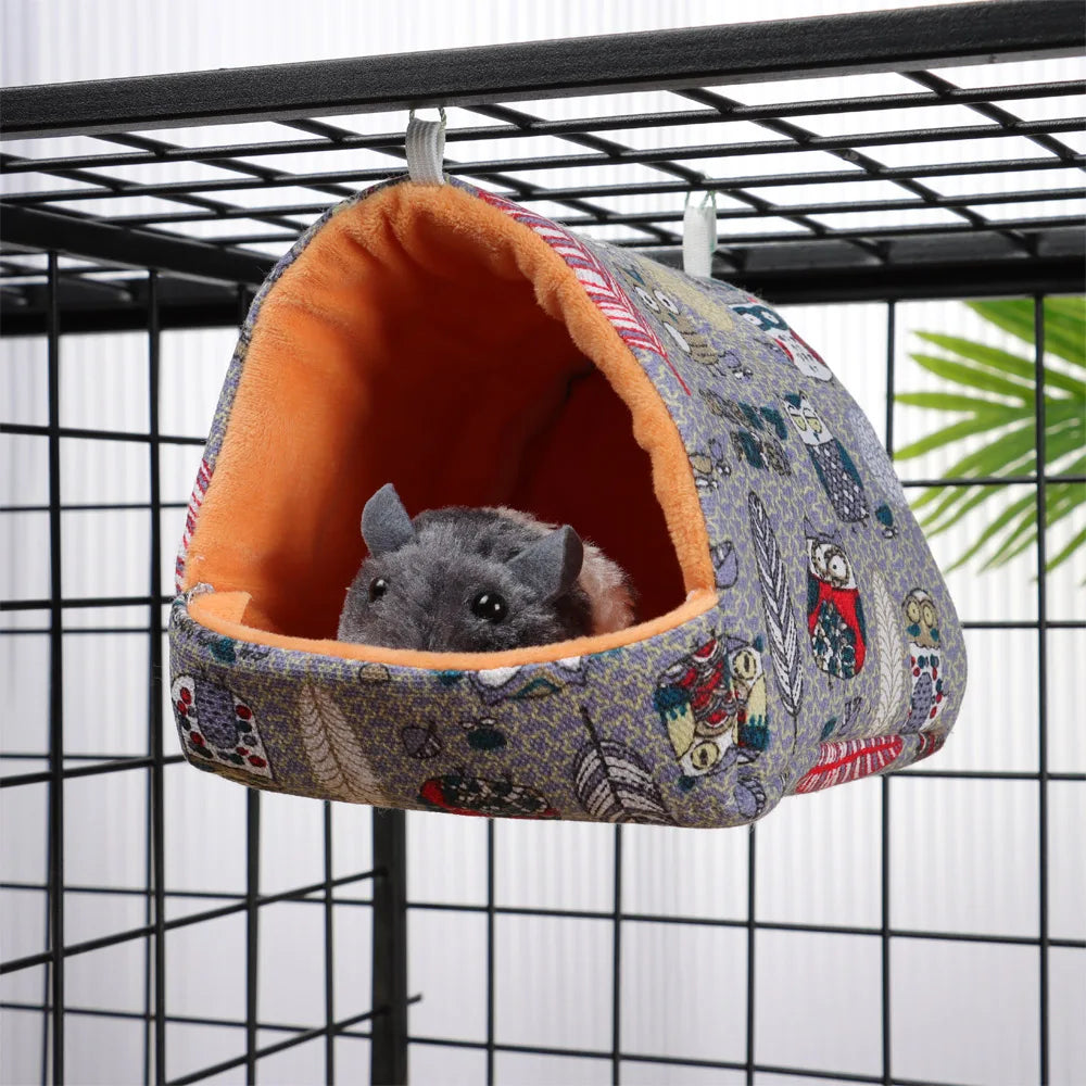 Small animal in a patterned hanging pet bed inside a cage
