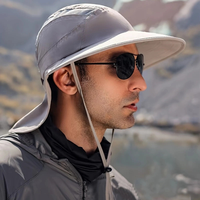 Man wearing a gray sun hat and sunglasses with a mountainous background