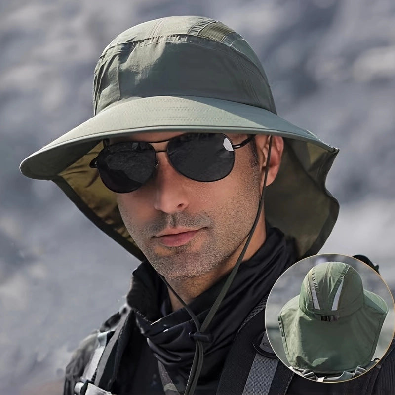 Man wearing a green bucket hat and sunglasses with a mountainous background