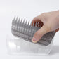 Hand holding a gray grooming comb over a transparent plastic container on a white background