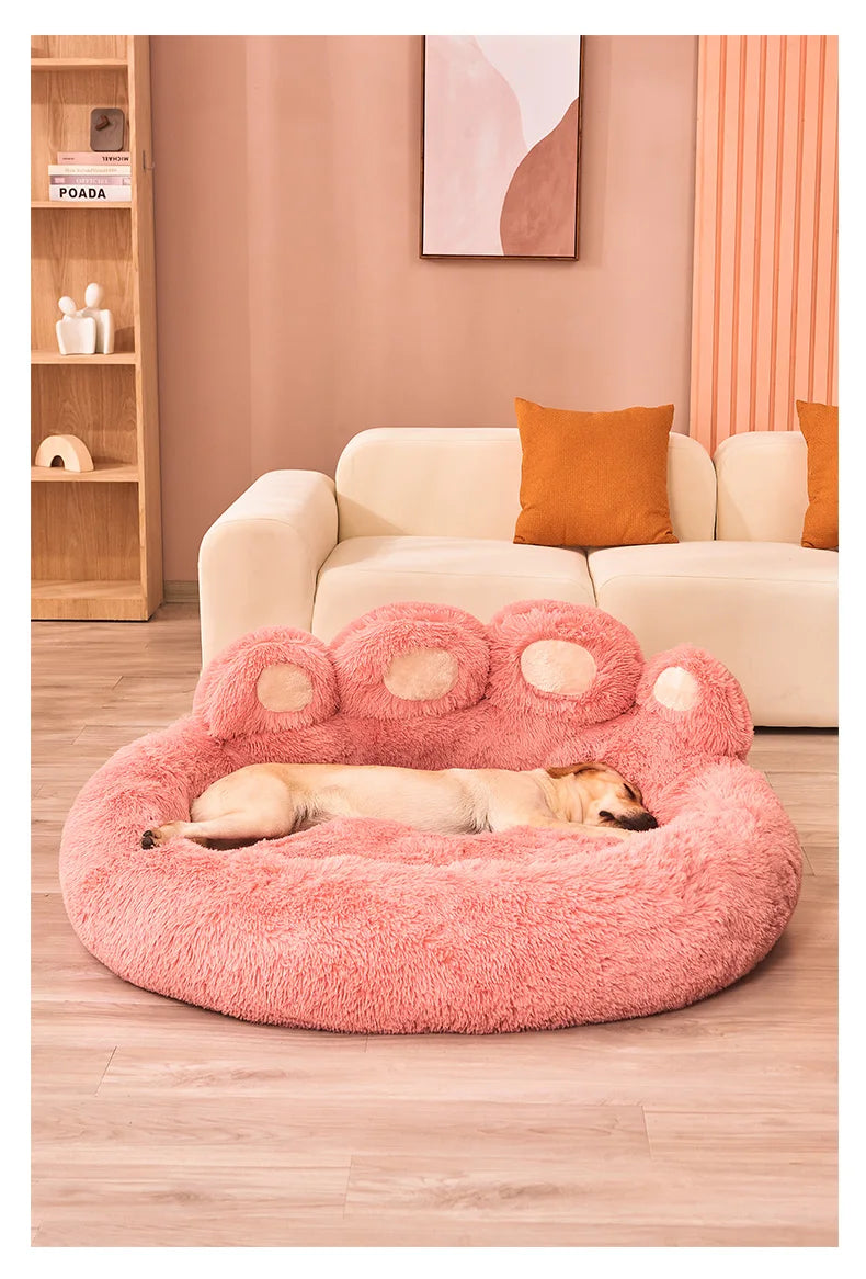 Pink paw-shaped pet bed with a dog inside in a living room setting.