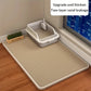 Cat litter box with a mat on a wooden floor next to a window.
