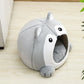 Gray raccoon-shaped pet bed on a wooden floor