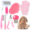Set of pet grooming tools including brushes, a comb, and a glove with a rabbit sitting next to them on a white background.