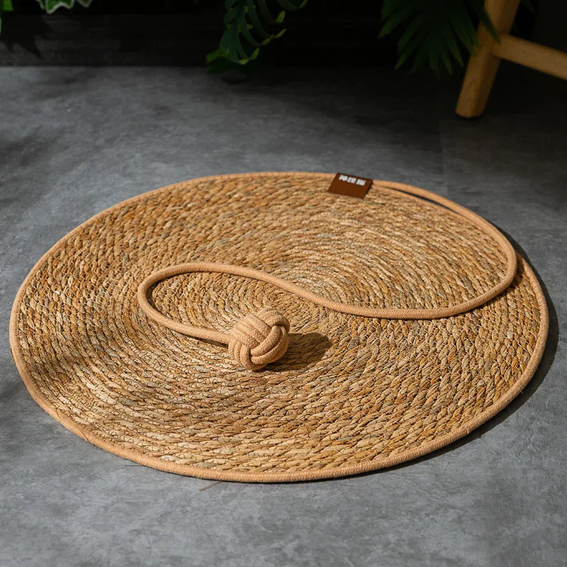 Round woven mat with a rope handle on a gray surface