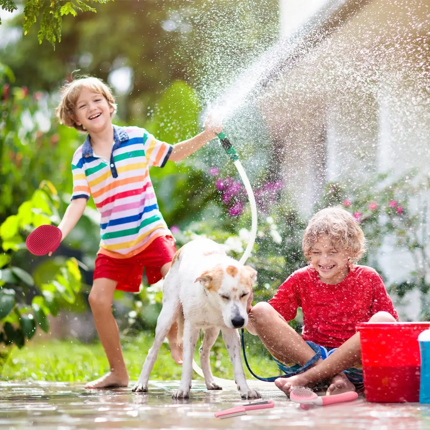 Two children playing with a hose and a dog in a garden