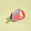 Retractable dog leash with red handle and gray reel on a light yellow background