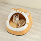 Cat playing with a toy inside a round, beige pet bed with white accents on a beige carpet.