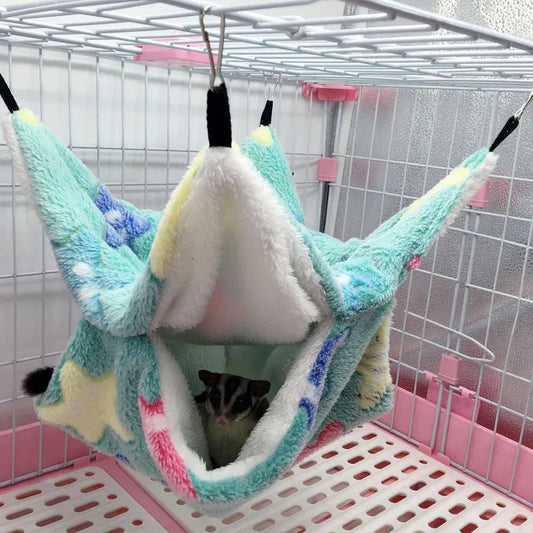 Colorful pet hammock hanging inside a cage with a small animal peeking out.
