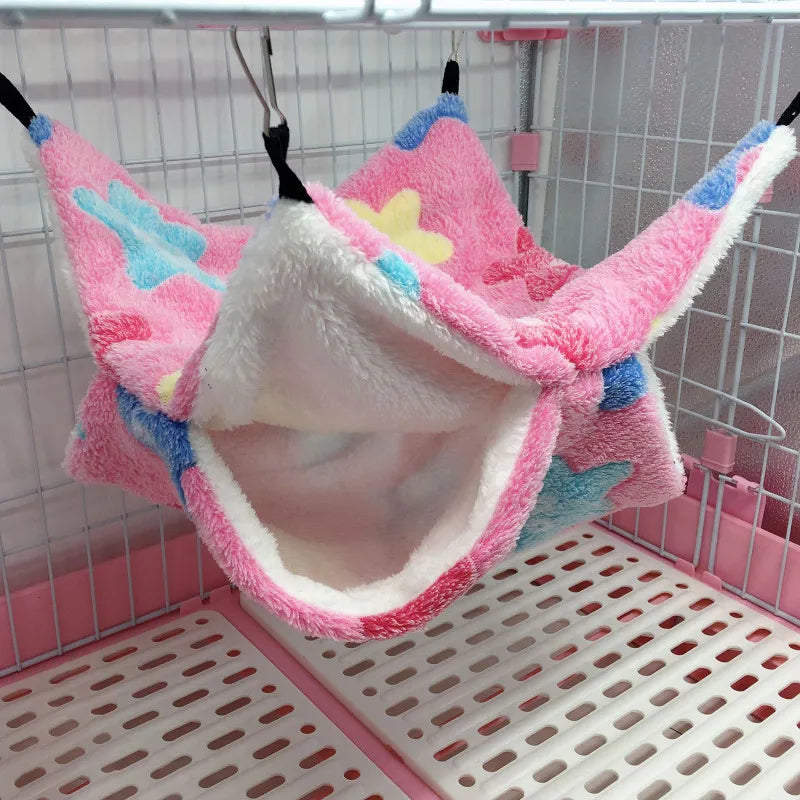 Pink pet hammock with colorful accents hanging inside a pet cage.