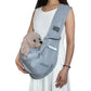 Person holding a gray pet sling with a small dog inside on a white background