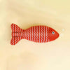 Red fish-shaped toy with white pattern on a beige background
