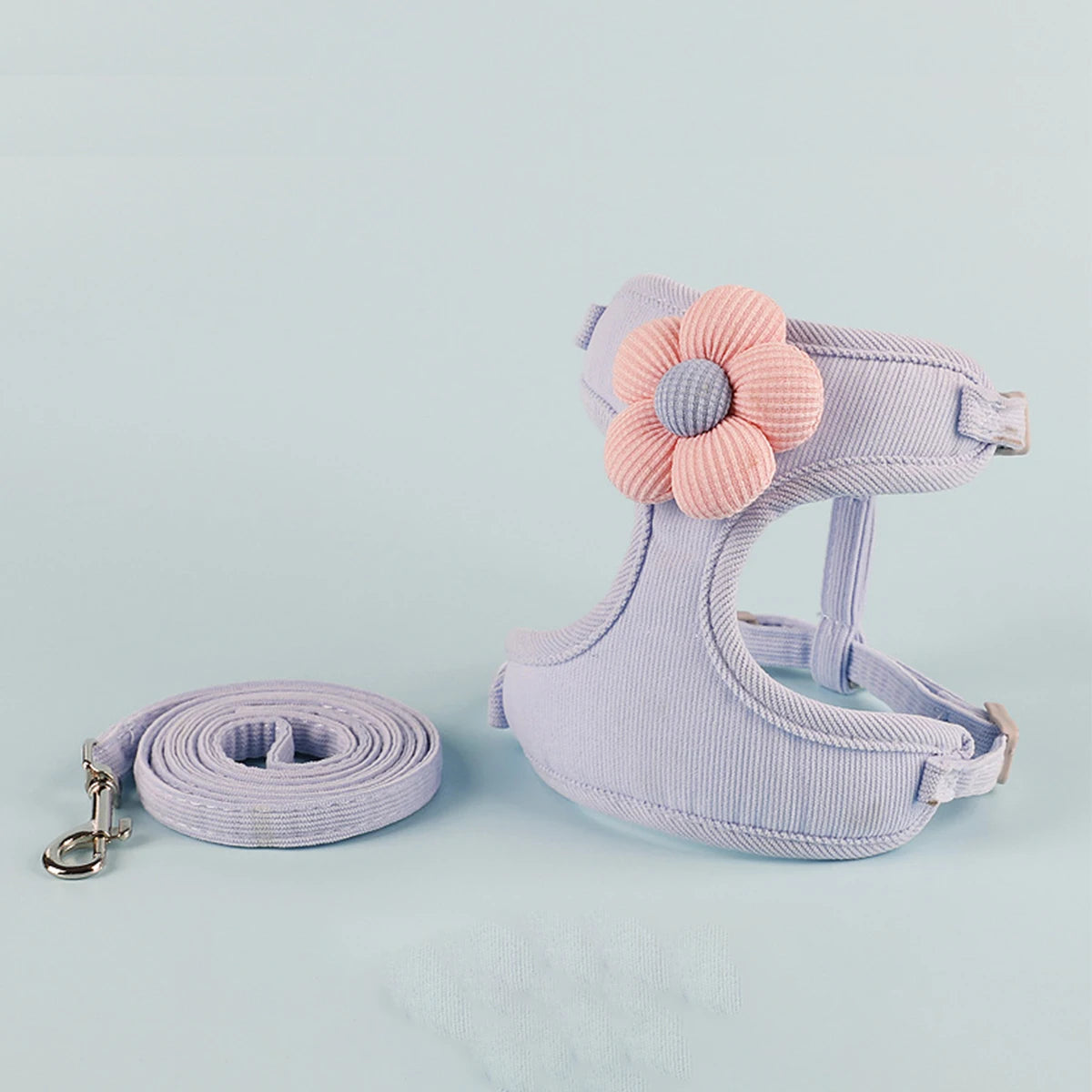 Dog harness with pink flower and matching leash on a light blue background