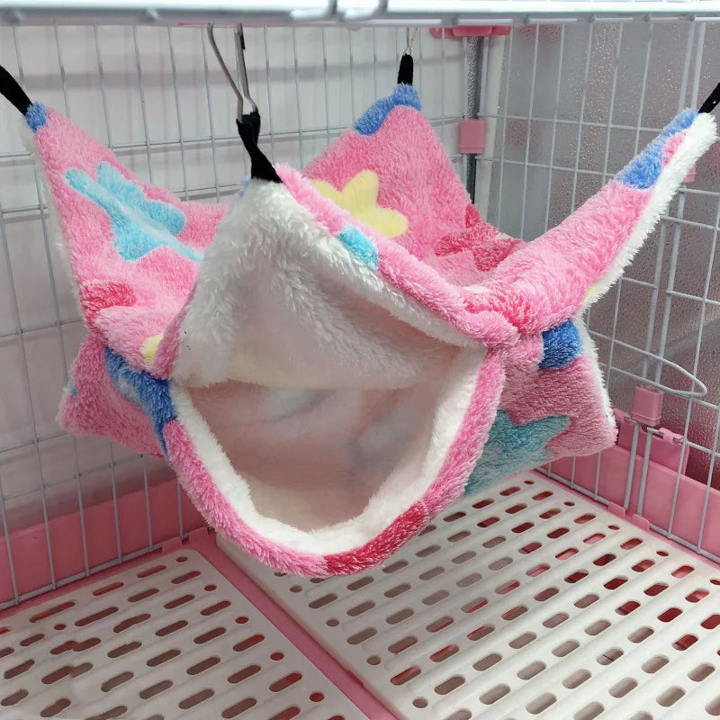 Pink pet hammock with colorful patterns hanging inside a pet cage.