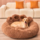 Dog lying on a brown fluffy pet bed in a living room with a beige sofa and orange cushions.