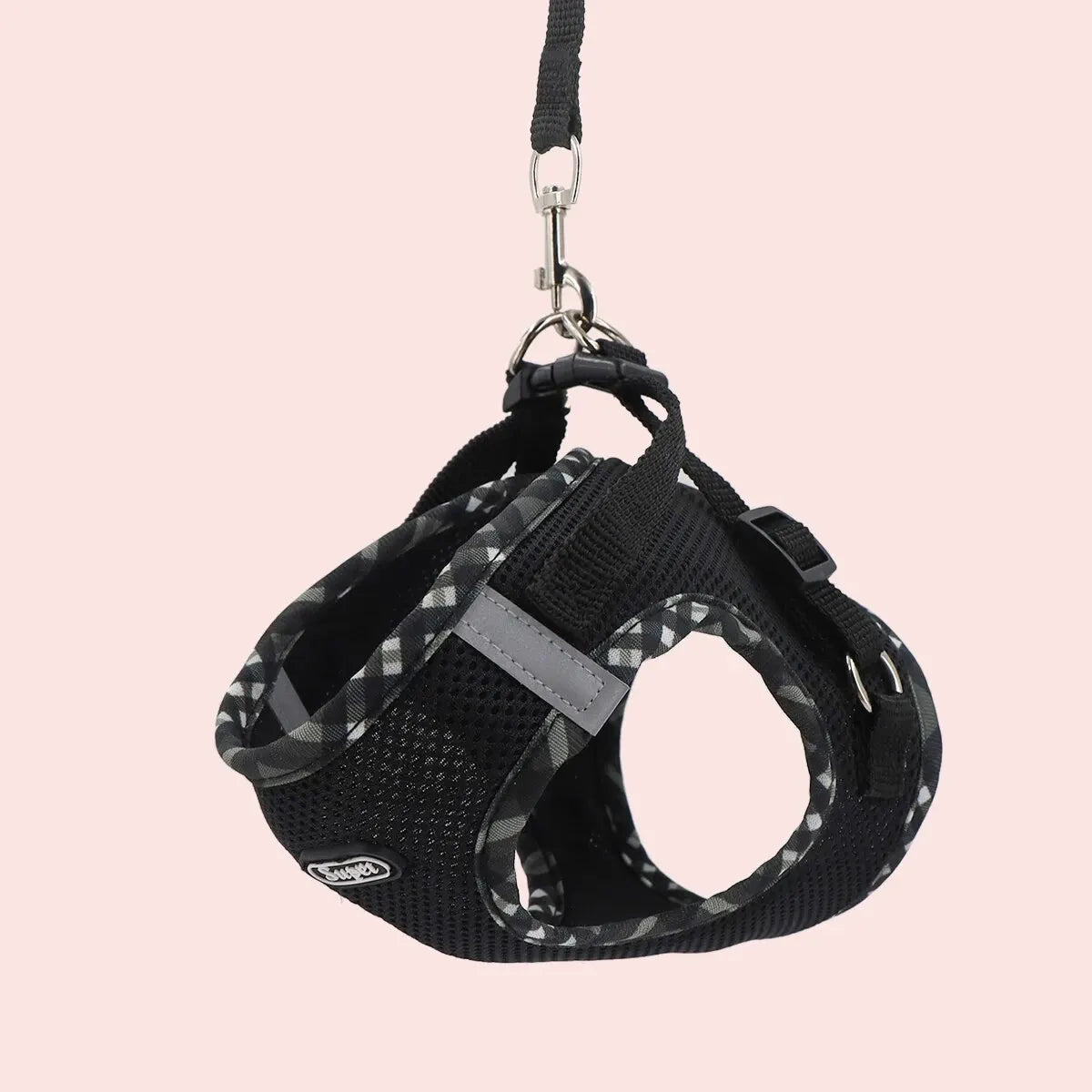 Black dog harness with gray accents on a pink background