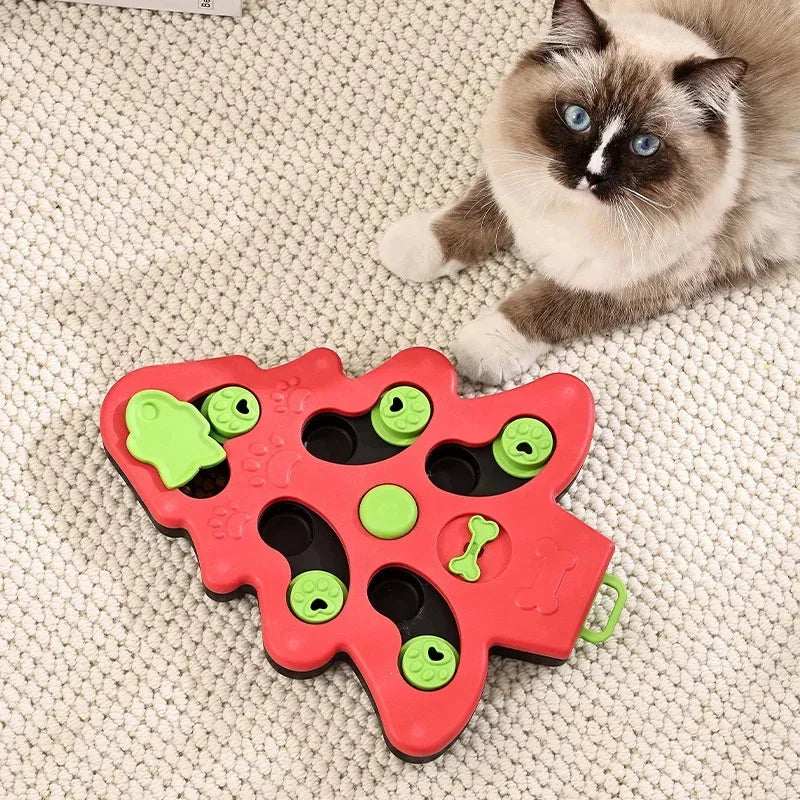 Red and green cat toy with a cat sitting next to it on a carpeted floor