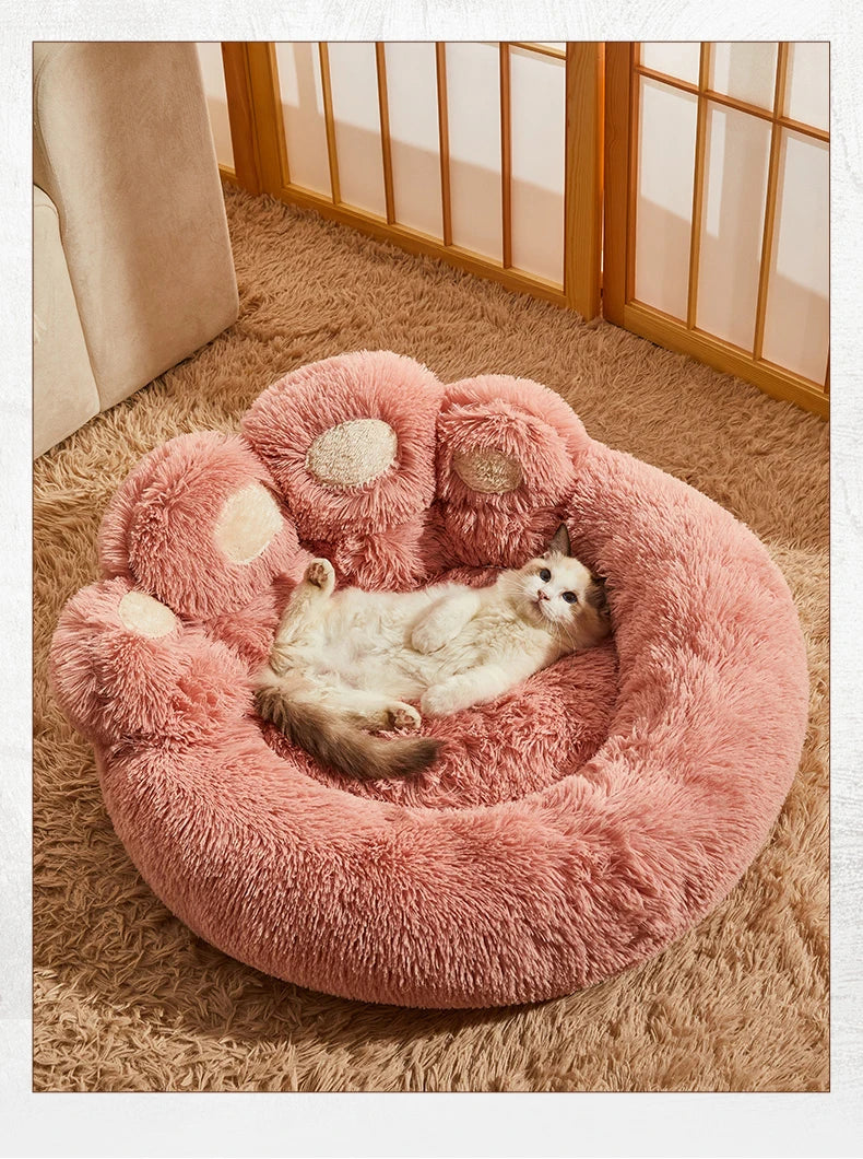 Fluffy pink pet bed with a cat inside on a carpeted floor.