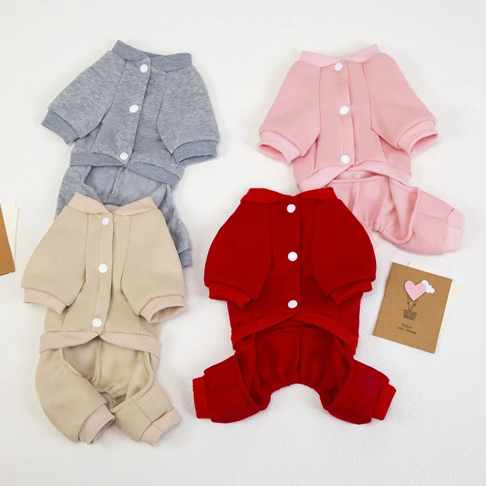 Four pieces of dog clothing in gray, pink, beige, and red on a white background.