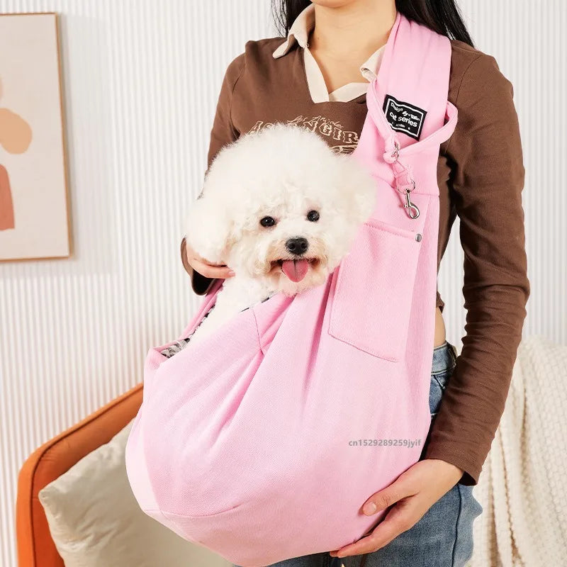 Person holding a small white dog in a pink sling against a neutral background