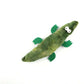 Green plush toy resembling a snake with leaf-like feet on a white background