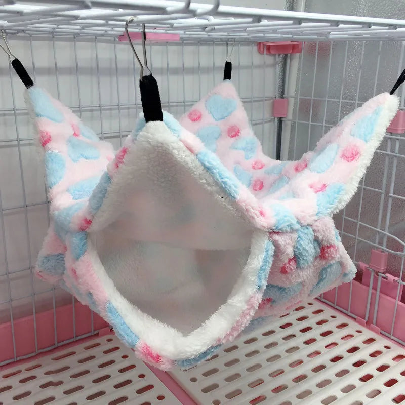 Plush pet hammock with heart patterns hanging inside a cage.