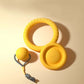 Yellow dog toy set with a ball, ring, and handle on a beige background