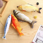 Four fish-shaped toys on a wooden surface with a straw hat and newspaper.