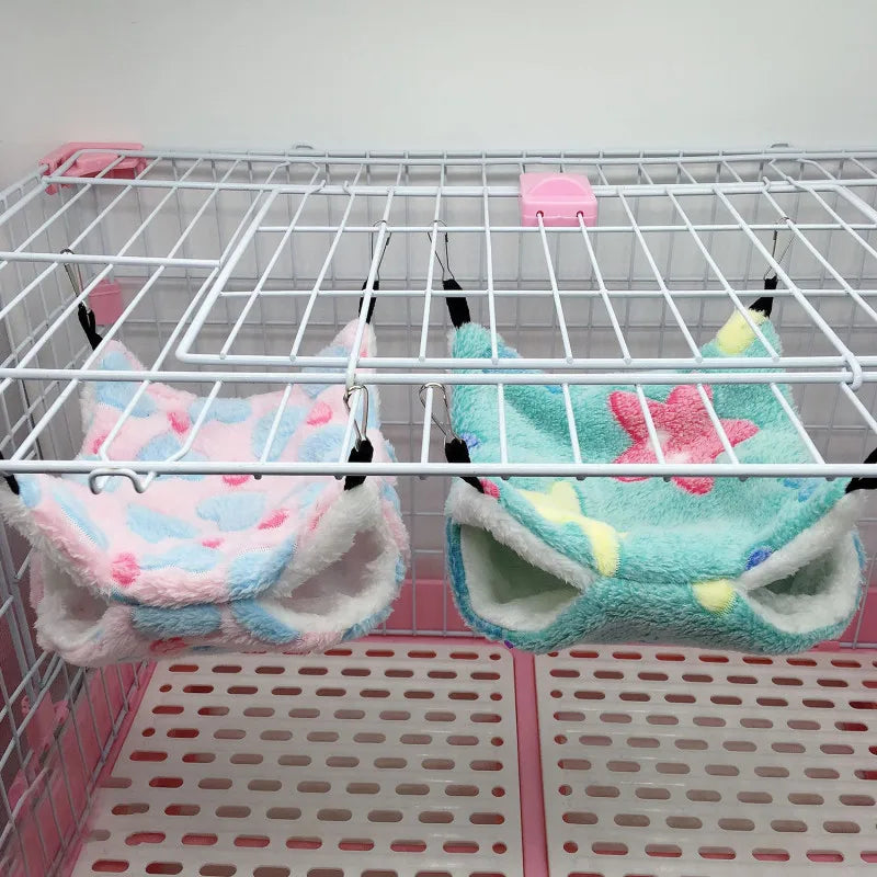 Colorful pet toys hanging on a wire rack inside a pink pet cage.