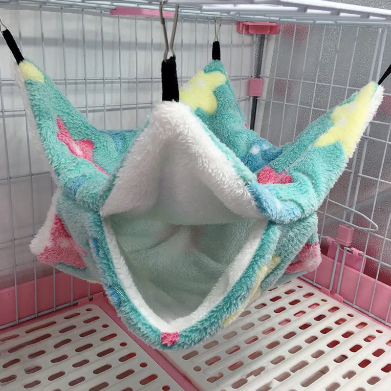 Colorful pet hammock hanging inside a cage with pink and white base.