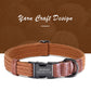 Brown woven dog collar with leather accents and engraved nameplate on a brown background with yarn balls.