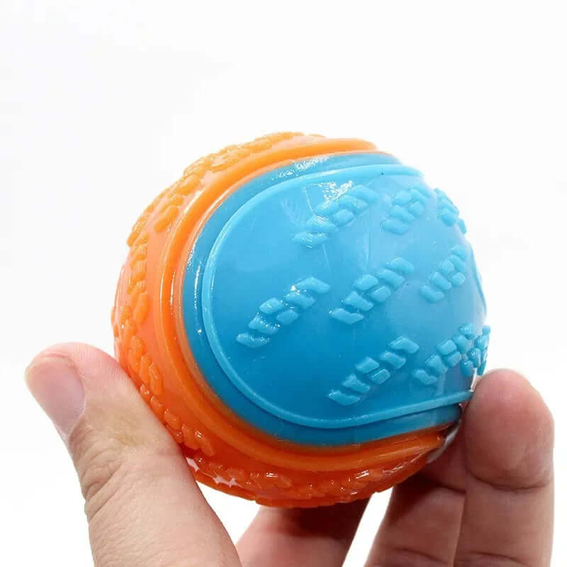 Orange and blue ball with textured surface held in a hand against a white background