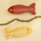 Two fish-shaped toys, one red and one yellow, on a beige background.