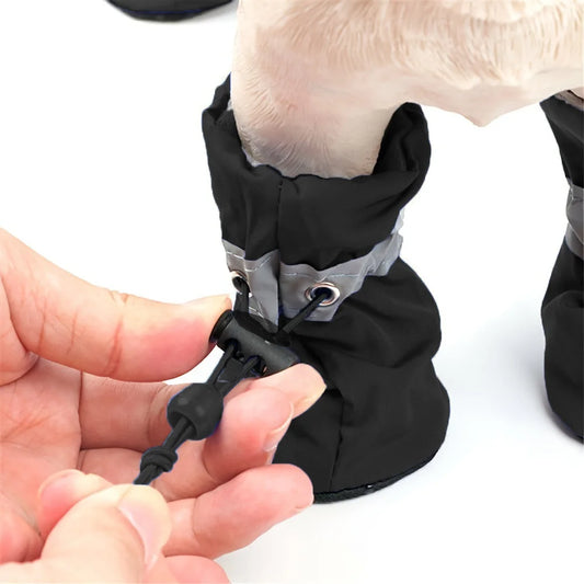 Black dog boot being adjusted by a hand on a white background